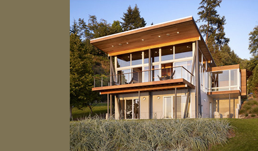 Vashon Cabin features a modern design with large windows, wood-paneled ceiling, and a balcony with cable railing.