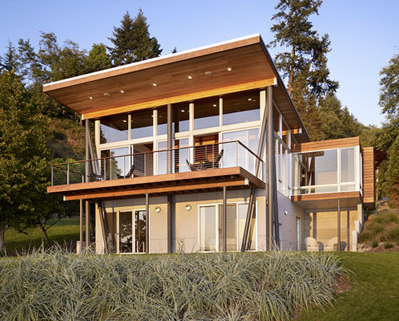 The Vashon Cabin shows a modern design with expansive floor-to-ceiling glazing and a prominent shed roof.
