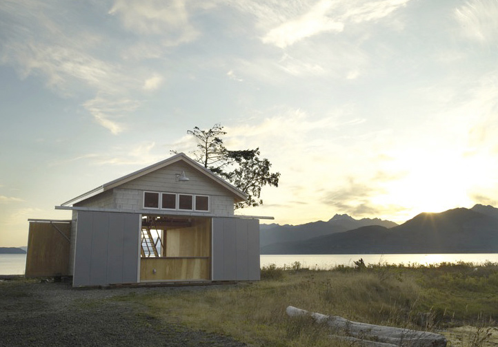 The Hood Canal Boat House features a gable roof and wood shingle siding with large open doors facing the water.