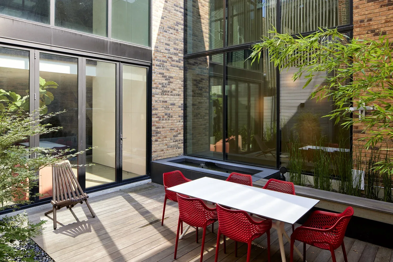 Outdoor courtyard with seating area and floor-to-ceiling glazing in brick residential building.