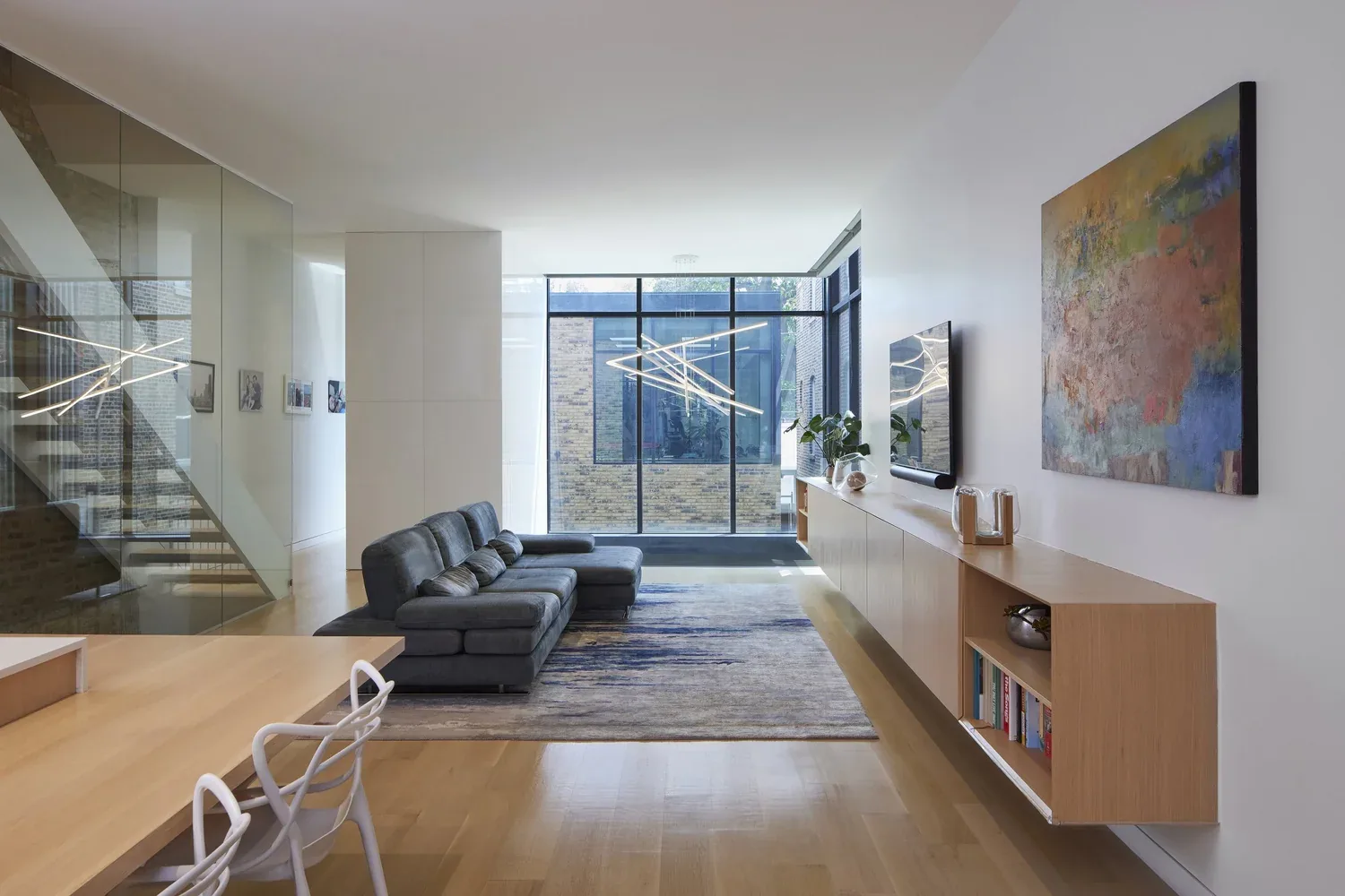 Living room featuring floor-to-ceiling glazing and a floating wood media console along one wall.