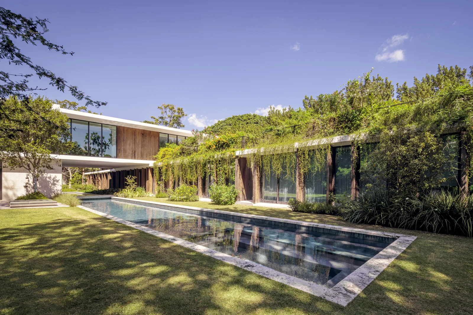 Kiaora Residence features a reflecting pool, vertical wood posts, and extensive greenery on green roofs and facades.