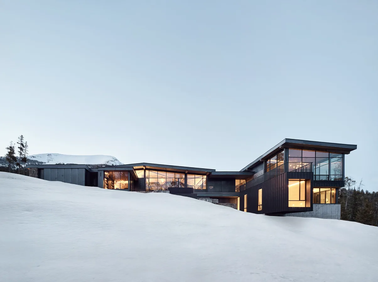 YELLOWSTONE project features large illuminated windows and a dark panel exterior on a snowy mountain site.