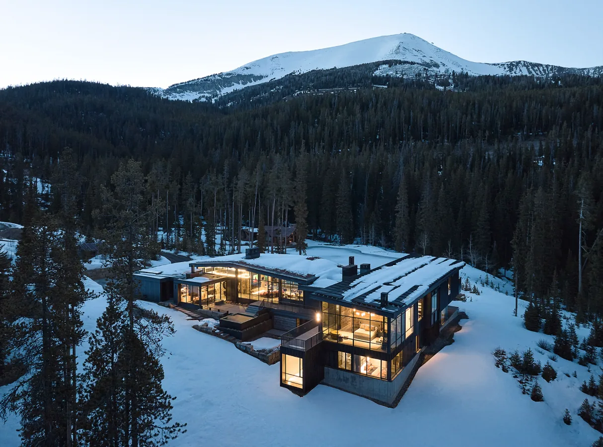 The 'Yellowstone' project by John Maniscalco Architecture features a modern home with extensive glazing and mountain views in a snowy forest setting.