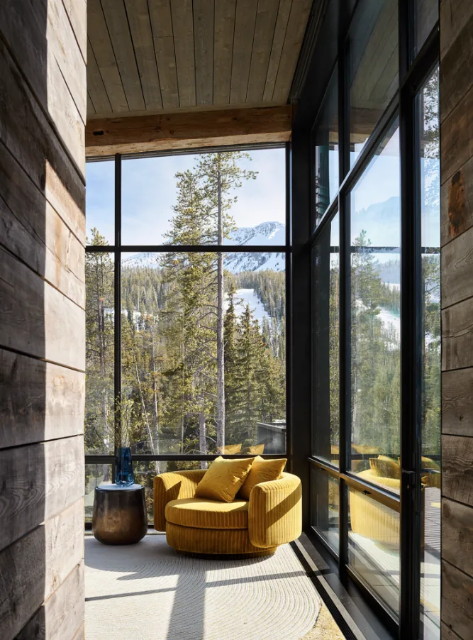 Seating nook with floor-to-ceiling glazing frames snowy mountain and forest views in the YELLOWSTONE project.