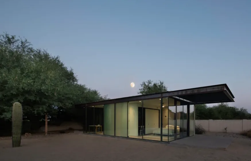 The ET Project by Audesign Studio features floor-to-ceiling glass walls and a flat roof, revealing a minimalist bedroom inside.
