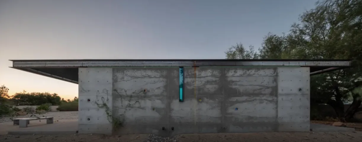The ET Project features a flat roof and concrete walls in a desert setting at dusk.