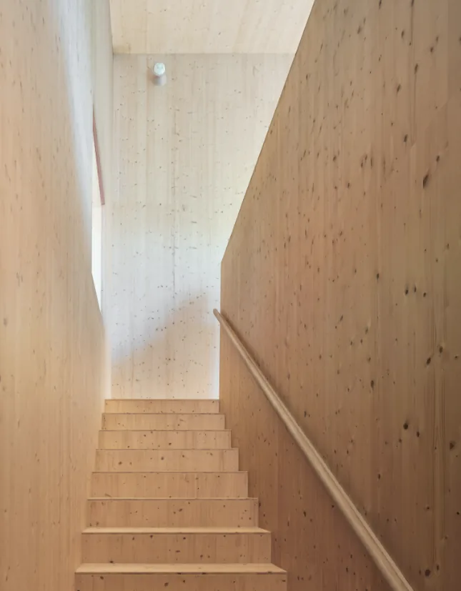 Interior stairway featuring light wood paneling and a minimalist wooden handrail at Hudson Valley House II.