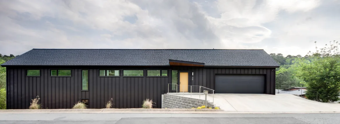 Exterior front view of a modern black house with gable roof and horizontal windows.