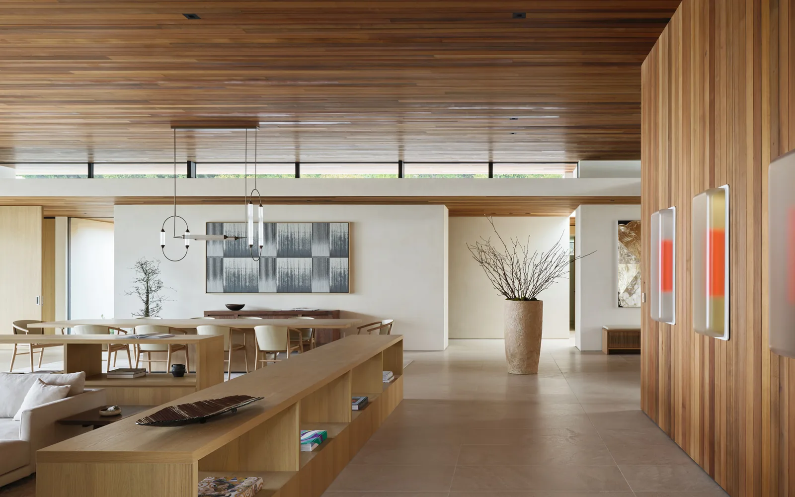 Interior of the Carla Ridge House shows a wood-paneled ceiling over an open dining and living space with modern lighting and art.