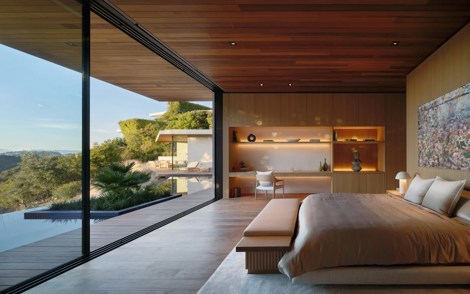 The Carla Ridge House bedroom features expansive glass walls and wood-paneled ceilings for seamless indoor-outdoor living.
