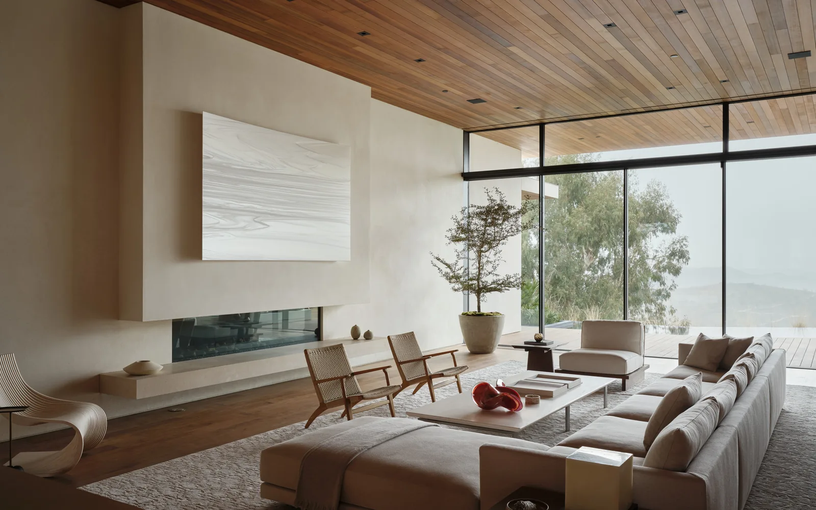 Living room of Carla Ridge House by Montalba Architects features a wood-paneled ceiling and a fireplace beneath wall art.