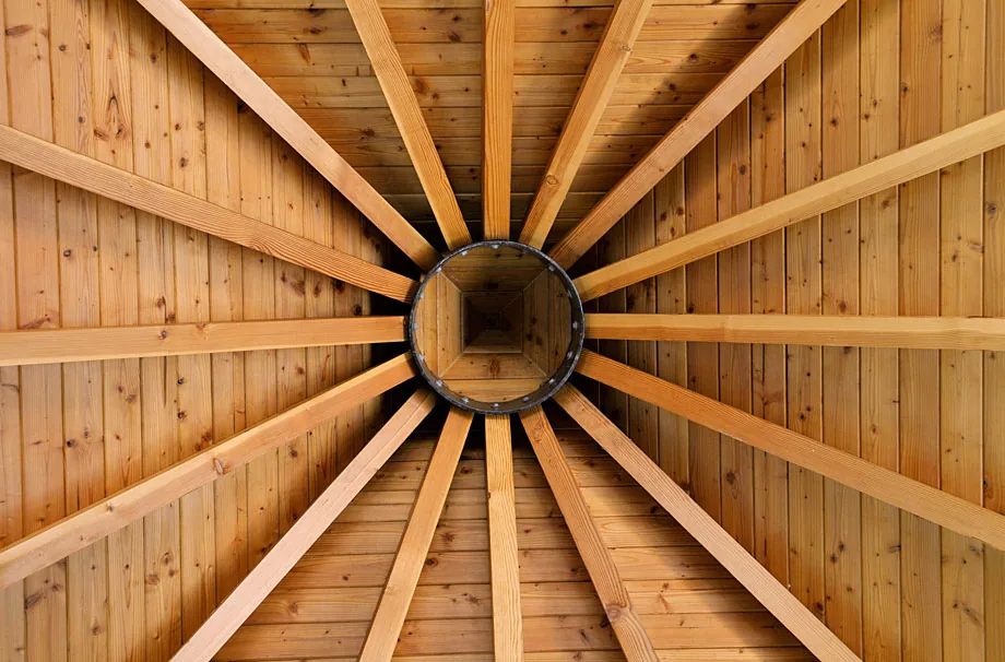 Peaked wood ceiling with radial beams and a central circular detail in the Garden Refuge project.