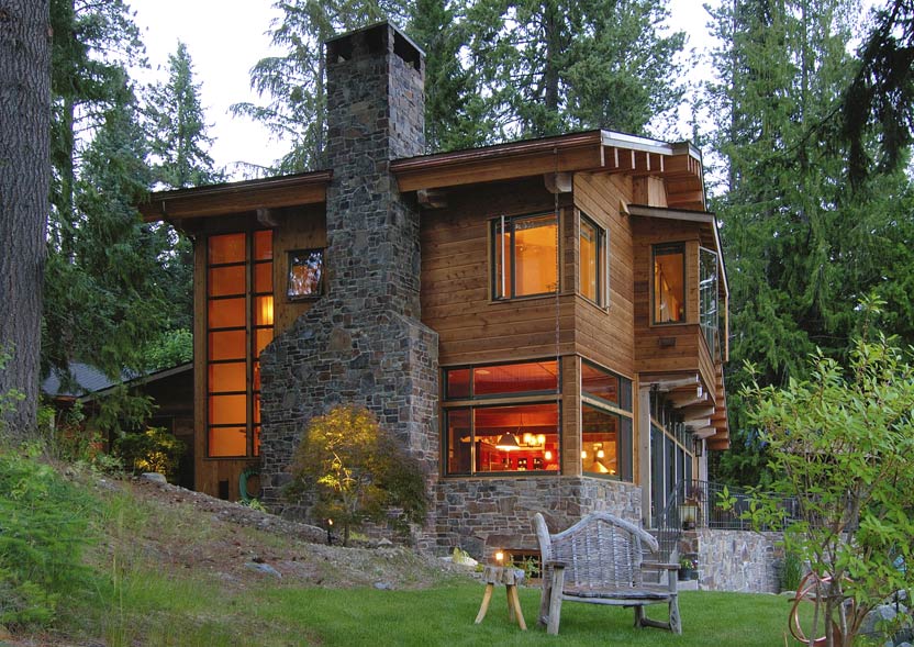 Borth House features wood siding and a large stone chimney with extensive windows, set in a forested landscape.