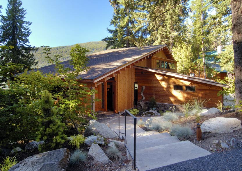 Borth House features wood siding with a slate chimney, corner windows, and is surrounded by a landscaped garden.