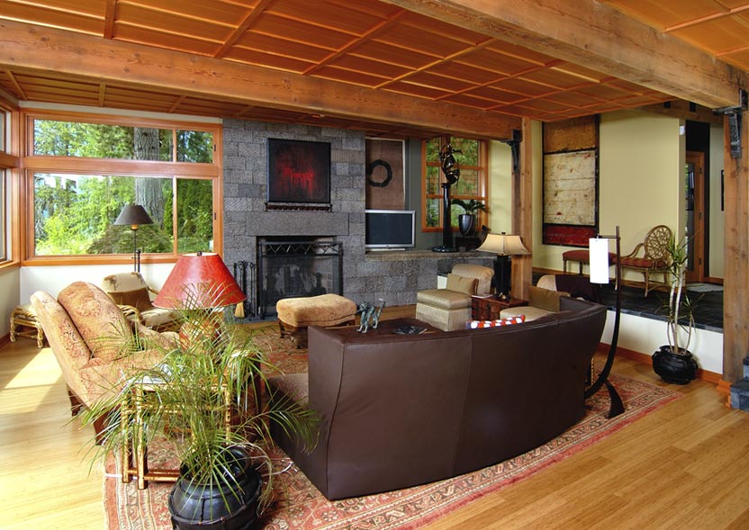 The Borth House living room features a wood-beamed ceiling, extensive glazing, and a stone fireplace.