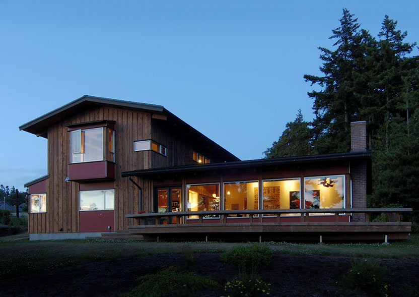 Omnell Residence features vertical wood siding and floor-to-ceiling glazing along the main floor, designed by SHKS Architects.