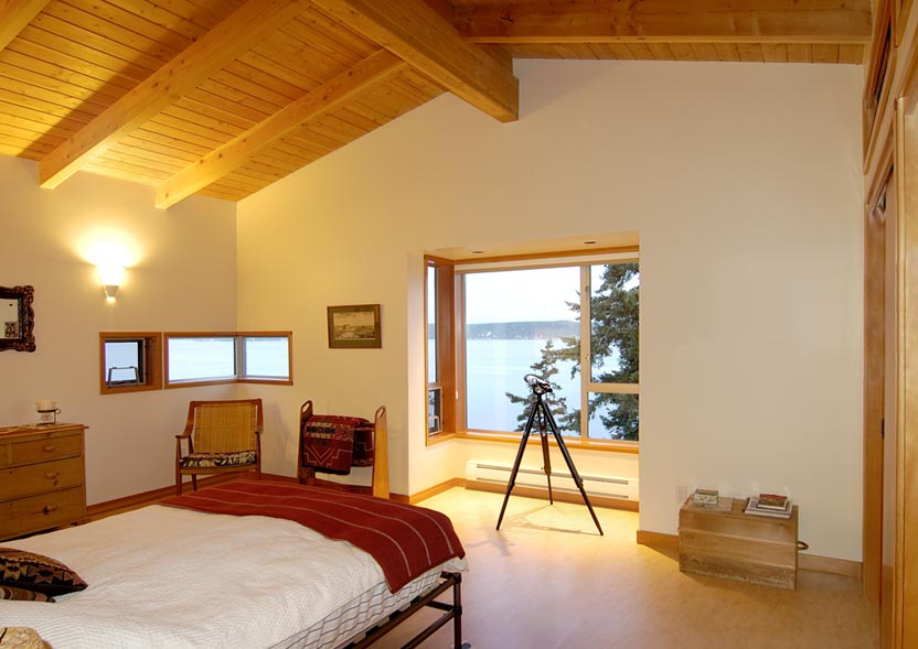 Interior bedroom with vaulted ceiling, wood trim, and large window view of waterfront at the Omnell Residence.