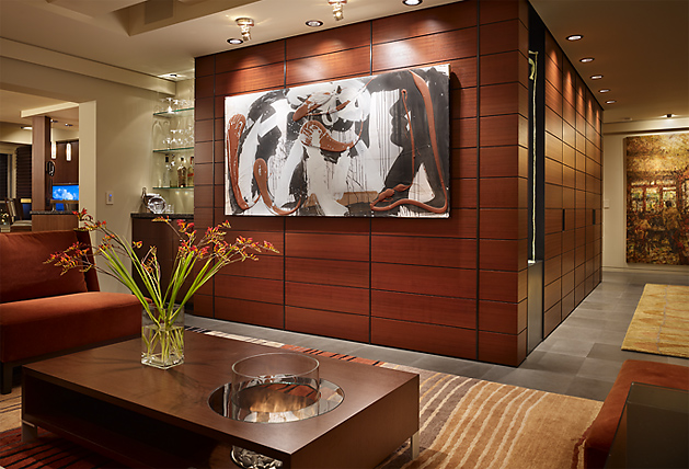 Living room in Watermark Tower Condominium featuring wood paneling, artwork, and recessed ceiling lighting by Tyler Engle Architects.