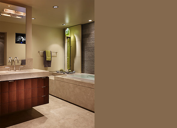 Bathroom featuring a built-in bathtub with decorative accents and a wood-paneled vanity with a polished countertop.