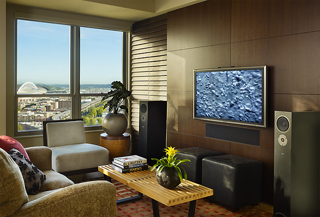 Living room in Watermark Tower Condominium with wood paneling and large city view window.