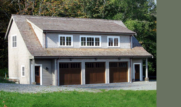 Two-story garage with three dark wood garage doors and upper windows under a gable roof.