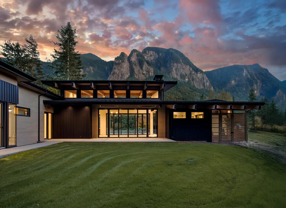 Exterior rear view of Echo Ridge House at dusk with mountain backdrop, showing a modern single-story structure with clerestory windows and a