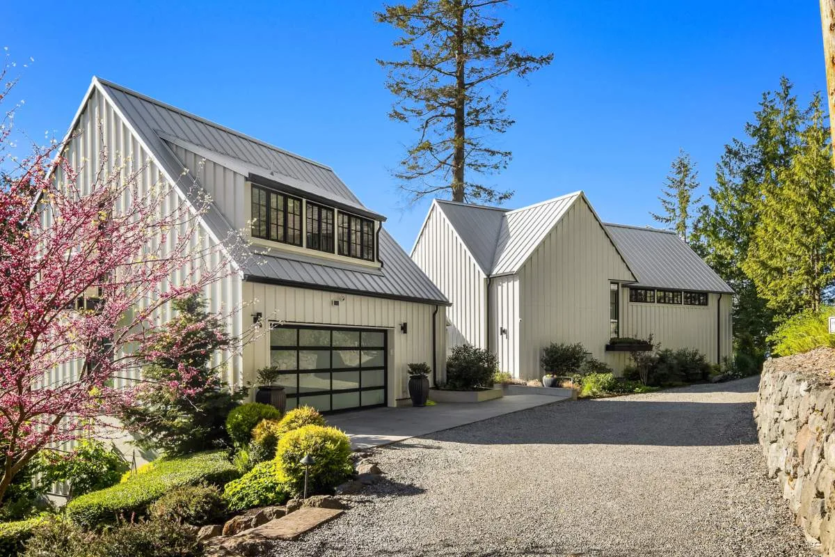 Exterior view of Lafayette House showing two white buildings with standing seam metal roofs and a gravel driveway under a clear blue sky.
