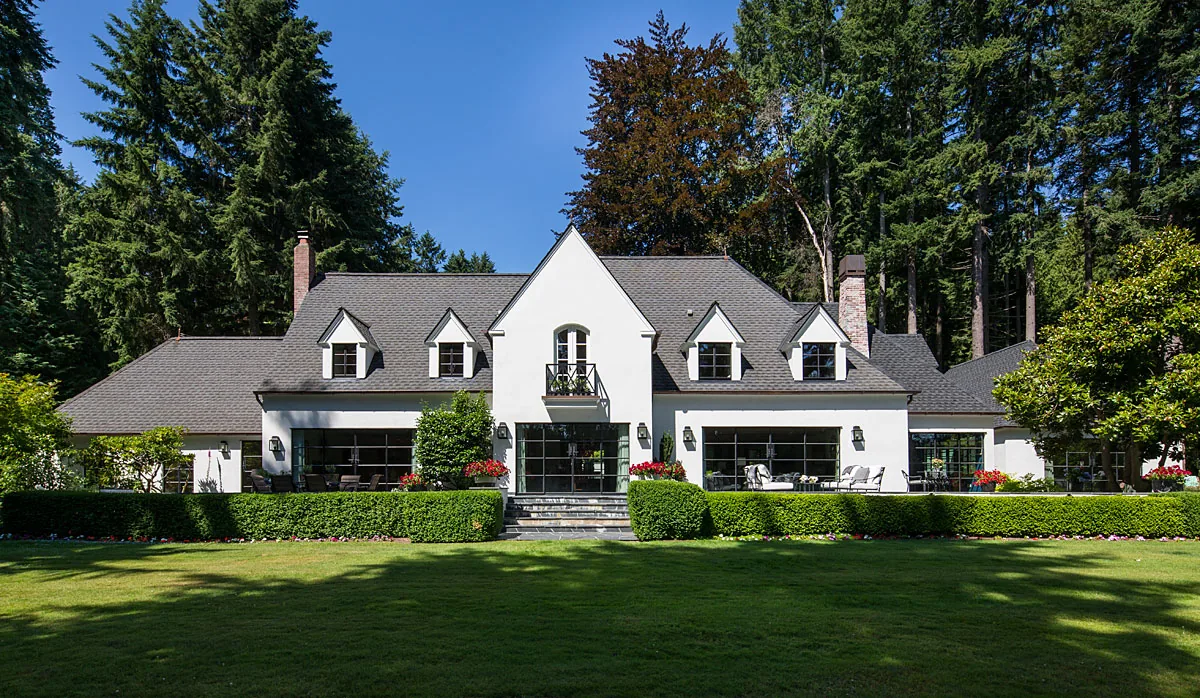 Front exterior view of the Manzanita Bay House with symmetrical gabled roofs and manicured lawn.