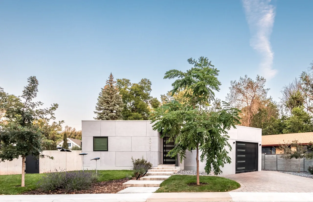 Front exterior view of a modern flat-roofed house with minimal detailing and a paved driveway.