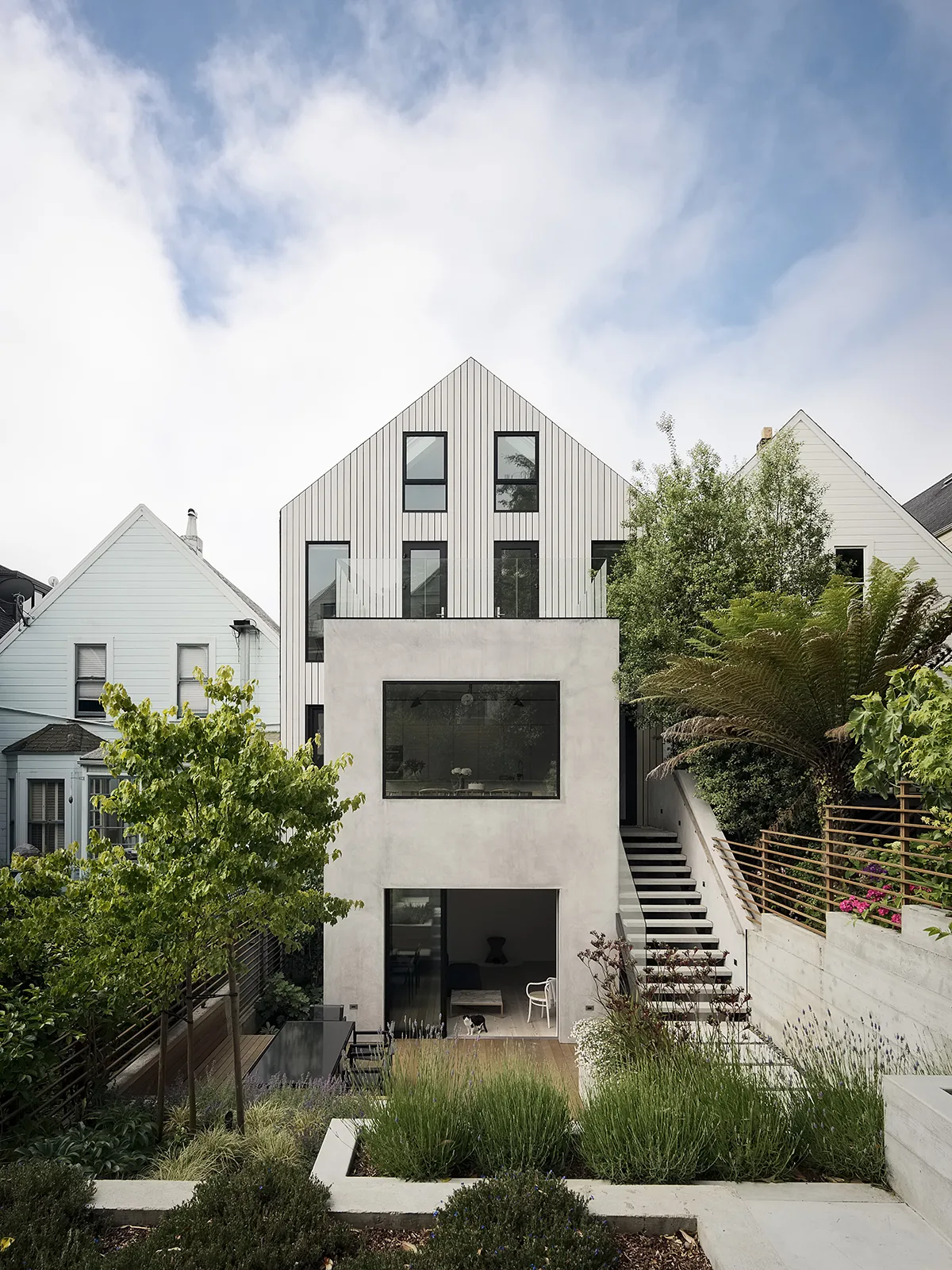 Straight on view of a modern gable-roof house with a concrete lower level and vertical siding on the upper floors.