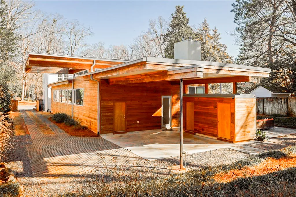 Exterior view of a modern wood house with an extended flat roof and carport area.