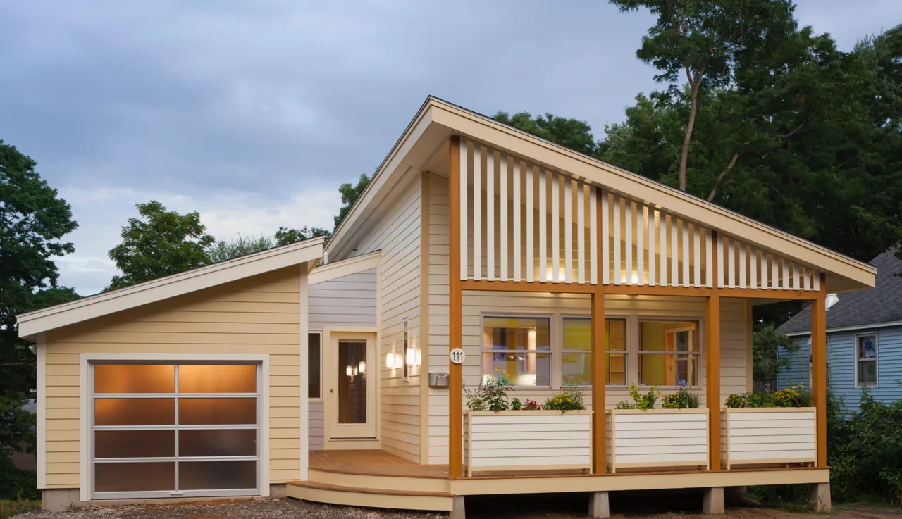 Modern small house with slanted roof and attached garage at dusk.