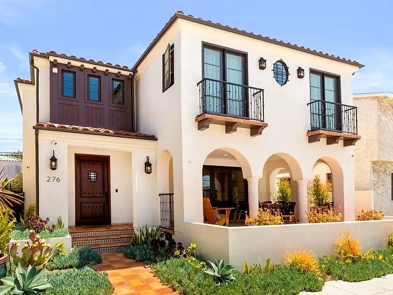 Front exterior view of a two-story Mediterranean-style home with arched porch and balconies.