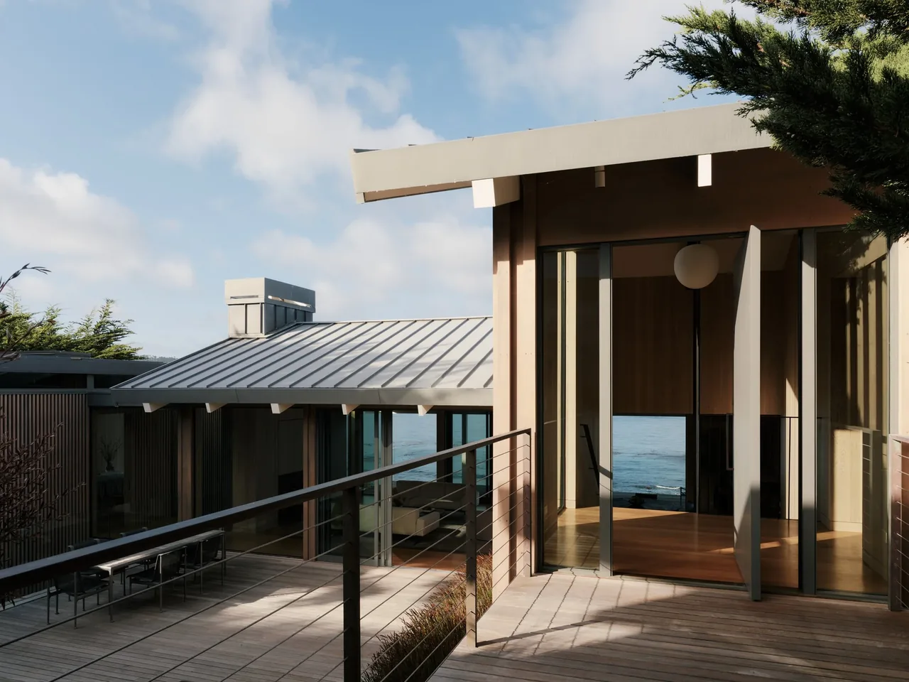 Exterior view of a modern home with floor-to-ceiling glass doors opening to a wooden deck and overlooking a body of water.