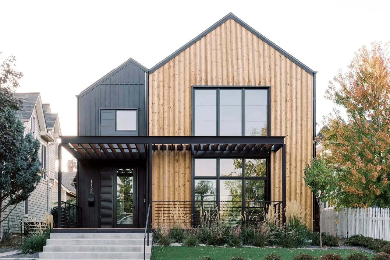 Two-story residence with vertical wood siding and large black-framed windows under a gable roof.