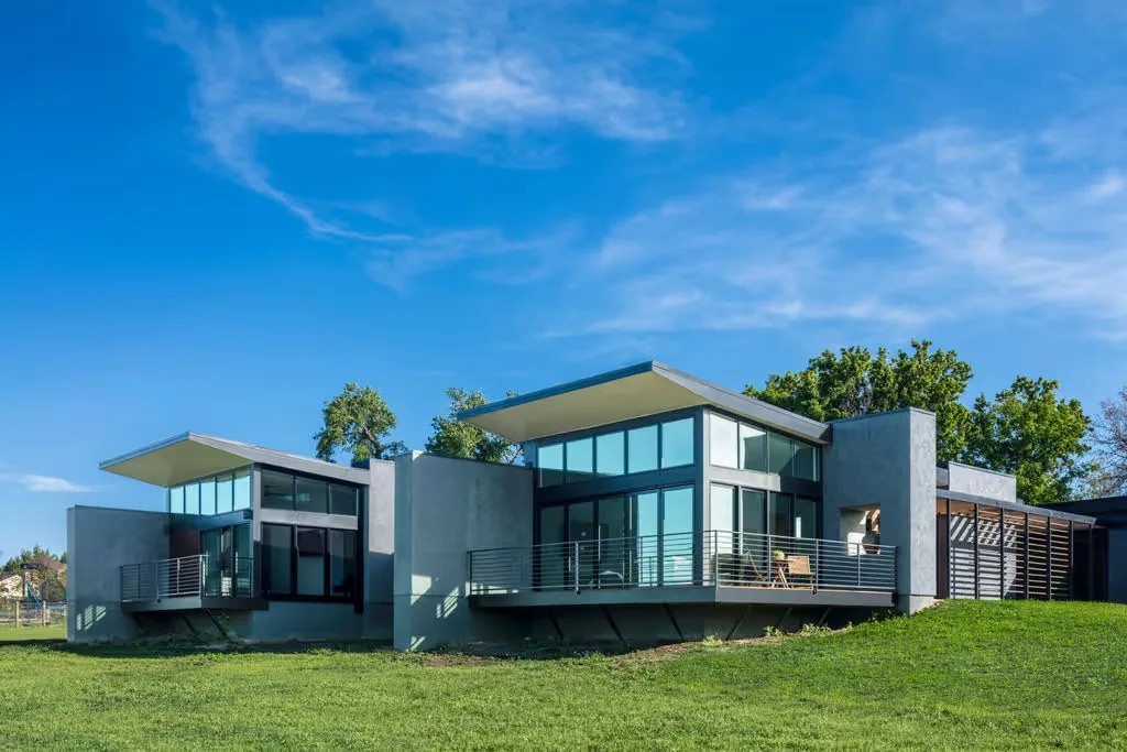 Modern residence with cantilevered wings, large floor-to-ceiling windows, and flat roofs against a blue sky.