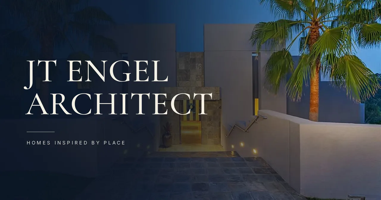 Nighttime view of a modern estate entry with stone flooring, palm trees, and illuminated stair railings.