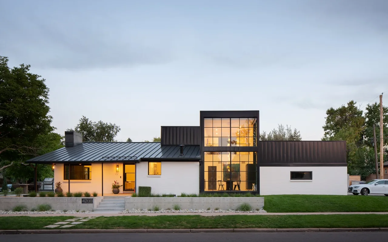 Front exterior of a modern black and white house with large vertical windows and a sloped metal roof.